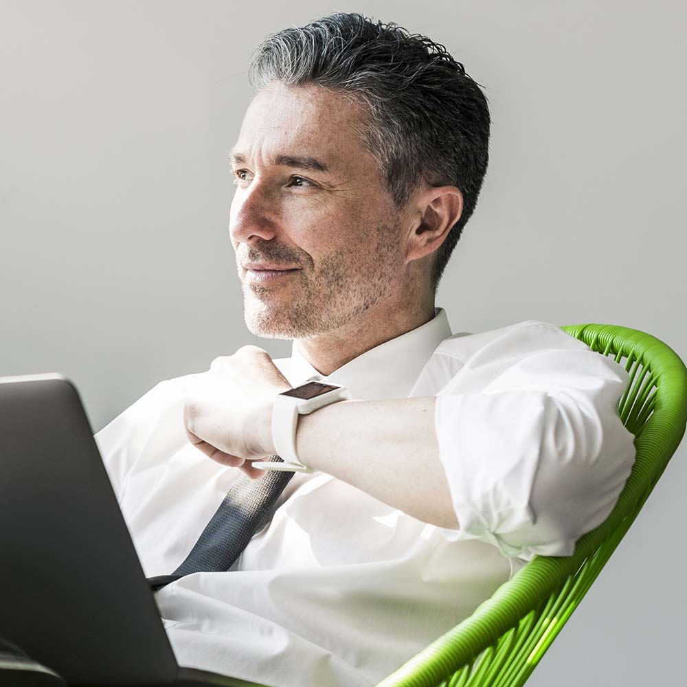 smiling-businessman-with-laptop-sitting-in-an-armc-XK37KKH.jpg